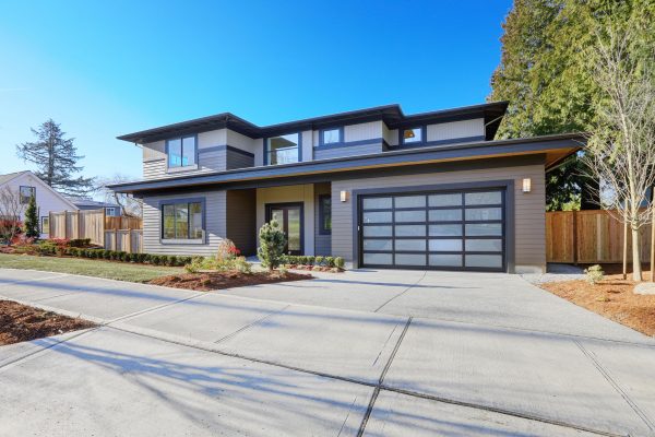 New construction home exterior with contemporary house plan  features low slope roof, brown siding and glass garage door. Northwest, USA